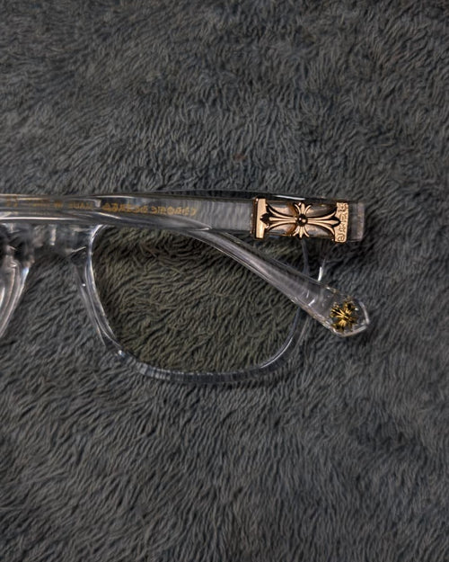 Clear eyeglasses with gold temple tips on a gray fur surface